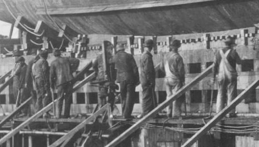 Workers wait under the hull to knock the bracing loose